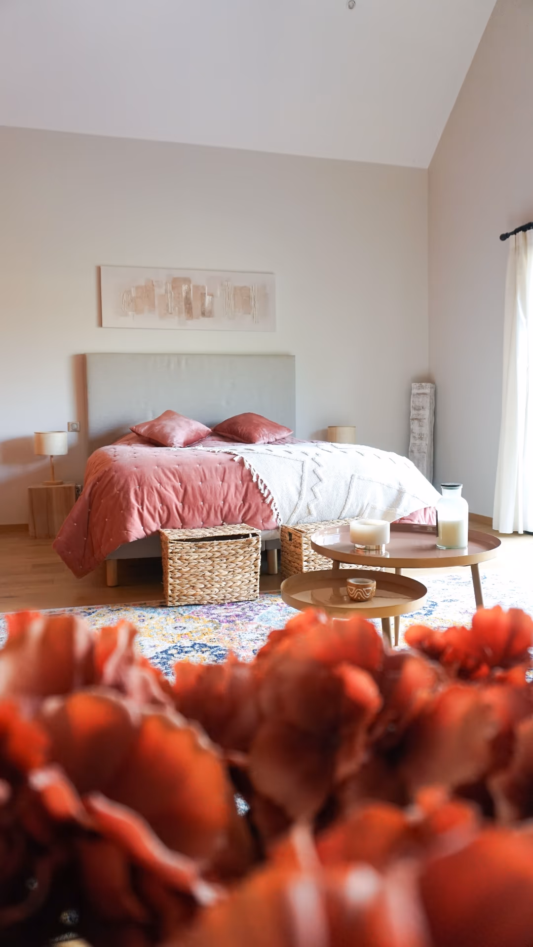 Chambre lumineuse avec linge rosé et décoration florale